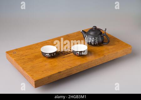 Due tazzine da tè asiatiche tradizionali e una teiera. Servizio su un tavolo di legno per cerimonie di tè. Il concetto di minimalismo. Foto Stock