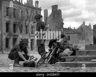 Francia settentrionale seconda guerra mondiale 1944 soldati britannici che guardano una bambola di bambini trovata con una bicicletta di civili che cercano di fuggire. FILE PIÙ GRANDI DISPONIBILI SU RICHIESTA Foto Stock