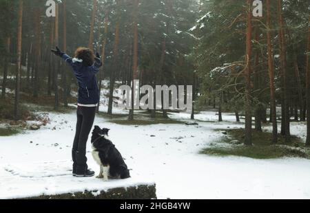Donna e cane si godono nel mezzo di una foresta nevosa. Nel Parco Nazionale della Sierra de Guadarrama, El Espinar, Segovia, Madrid. Foto Stock