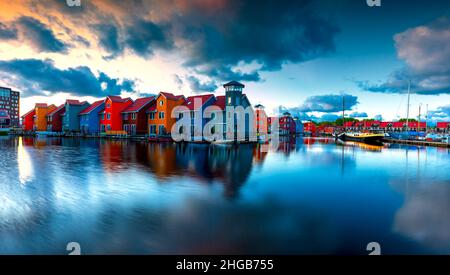 Porto di Groningen nei Paesi Bassi. Barche, case e bellissimo cielo all'alba riflesso nel mare. Ci sono delle nubi drammatiche nel cielo. Foto Stock