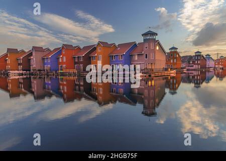 Porto di Groningen nei Paesi Bassi. Barche, case e bellissimo cielo all'alba riflesso nel mare. Ci sono delle nubi drammatiche nel cielo. Foto Stock