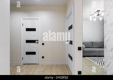 Corridoio interno con porte bianche in un piccolo monolocale Foto Stock
