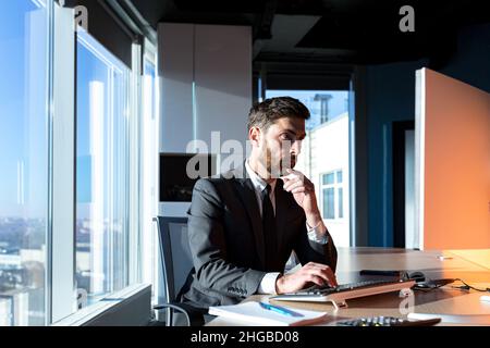 Pensava che l'uomo d'affari lavorava in ufficio al computer, concentrava l'uomo nei vestiti d'affari pensando a nuove attività Foto Stock