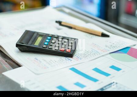 strumenti utilizzati da un contabile per bilanciare le finanze di una microimpresa. matita ecologica con un piccolo calcolatore nero in cima a un grafico delle vendite r Foto Stock