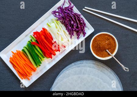 Ingredienti per i involtini primaverili vegani vietnamiti con carota, cetriolo, cavolo rosso, cipolline e salsa piccante. Mangiare sano Foto Stock