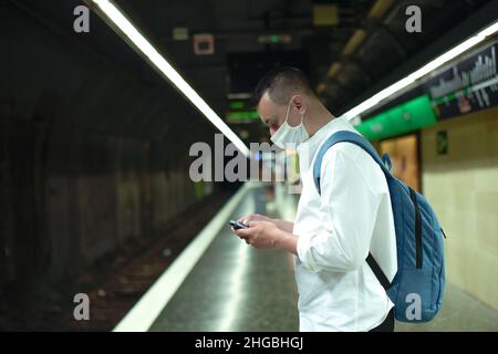 Un uomo mascherato si alza in metropolitana con un telefono nelle sue mani. Azioni contro kofid, indossando una maschera in luoghi pubblici. Foto Stock