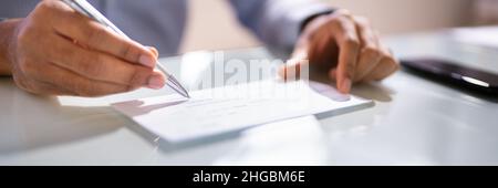 African Man Writing Money Check. Segno di spunta o assegno Foto Stock