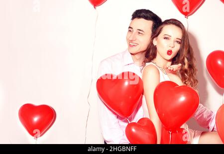 L'uomo con la sua bella ragazza di sweetheart danza e divertirsi al giorno di San Valentino dell'amante. Festa di San Valentino. Sfondo rosso palloncini cuori. Concetto di amore. Foto Stock