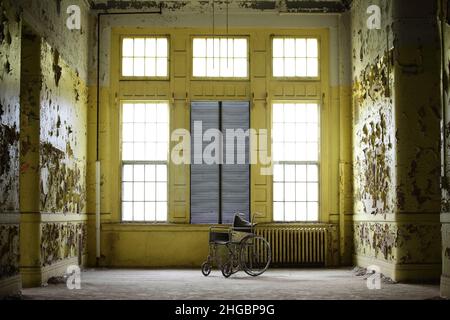 Sedia a rotelle singola nell'ala abbandonata di un ex ospedale psichiatrico Foto Stock