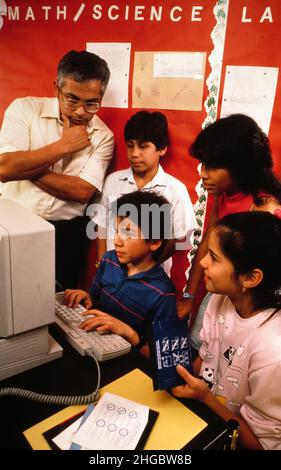 Austin, Texas USA 1990: Gli ispanici 5th si classificano al laboratorio di computer con la supervisione dell'insegnante. SIG. ES-035. Foto Stock