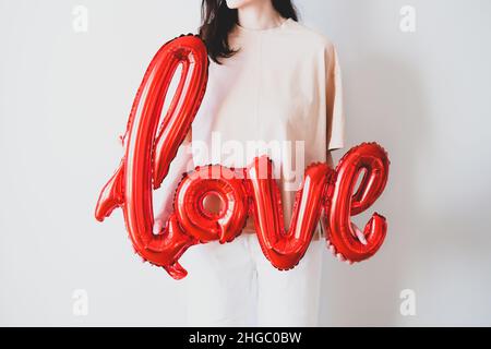 Donna con il palloncino rosso di lamina di amore nelle sue mani. Auguri per San Valentino, Festa della mamma, compleanno. Foto Stock