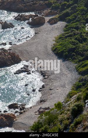 Una spiaggia rocciosa con acqua di mare schiumosa vista dall'alto in formato verticale Foto Stock