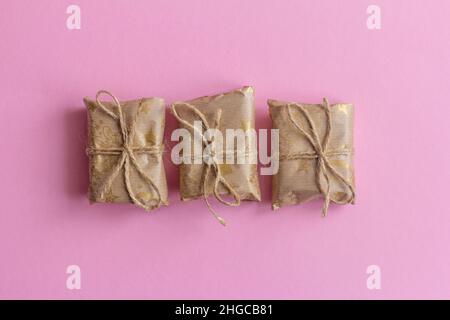 Tre pezzi di sapone fatto a mano, fatti con ingredienti naturali, in una confezione regalo su sfondo rosa Foto Stock