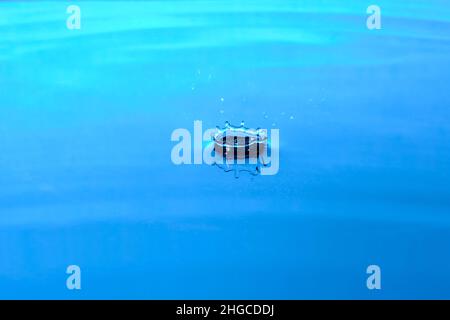 Spruzzi acqua dopo goccia cade.sfondo blu astratto con goccia in acqua Foto Stock