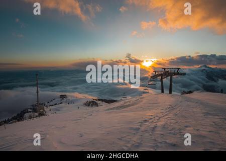 Cima della pista da sci di krvavec, bagnandosi con gli ultimi raggi di sole tramontare dietro le nuvole. Grande antenna tv visibile in cemento. Foto Stock