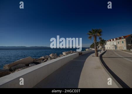 Bella passeggiata sul Bol na Bracu, sentiero pedonale che porta da Rat alla città di Bol, palme visibili e vecchie case. Foto Stock