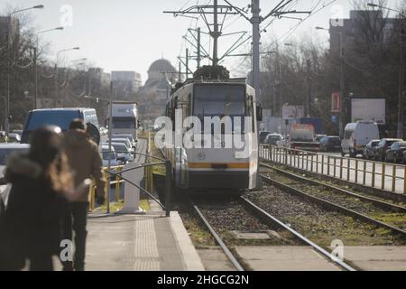 Bucarest, Romania - 19 gennaio 2022: Tram vecchio che arriva in una stazione su un viale di Bucarest in una soleggiata giornata invernale. Foto Stock