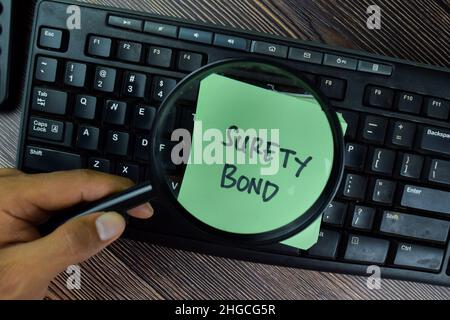 Surety Bond scrivere su note appiccicose isolate su tavola di legno. Foto Stock