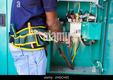 Primo piano di un elettricista incontrollabile che lavora utilizzando attrezzi o attrezzature per manutenzione o riparazione - concetto di controllo dei collegamenti Foto Stock