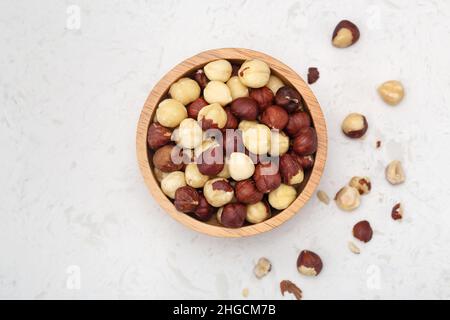 Nocciole in ciotola di legno su sfondo di marmo, vista dall'alto Foto Stock