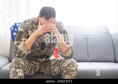 soldato triste in uniforme camuffata che tiene il tag militare in clenched mani Foto Stock