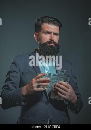 Barman o barman serve cognac. Uomo d'epoca retrò con whiskey o scotch. Uomo sommelier. Uomo sicuro e ben vestito con un bicchiere di whisky. Foto Stock