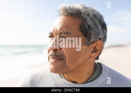 Primo piano dell'anziano biraciale in pensione che guarda via mentre pensa alla spiaggia durante la giornata di sole Foto Stock