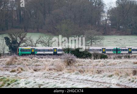 La mattina presto passa in treno per Southern Railway, che passa attraverso i campi ricoperti di gelo in una fredda mattina invernale a West Sussex, Inghilterra, Regno Unito. Foto Stock