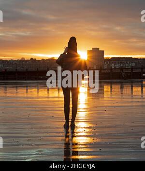 Portobello Edimburgo, Scozia, Regno Unito. 20th gennaio 2022. Nuvoloso alba per questi due studenti cinesi, da Glasgow dove stanno studiando, visitando Edimburgo per vedere il colore dell'alba al mare dal Firth of Forth. Temperatura un freddo 3 gradi centigradi. Credit: Archwhite/alamy live news. Foto Stock