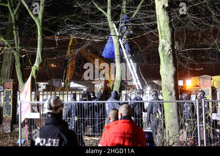 Amburgo, Germania. 20th Jan 2022. Un poliziotto si erge su una scala da un albero precedentemente occupato. Gli attivisti hanno protestato all'inizio del giovedì mattina contro la caduta di alberi a Neuer Pferdemarkt a St. Pauli. Tre persone erano salite negli alberi per impedire il lavoro di abbattimento, ha detto la polizia. Inoltre, molti altri attivisti si erano riuniti nel sito. Credit: Bodo Marks//dpa/Alamy Live News Foto Stock