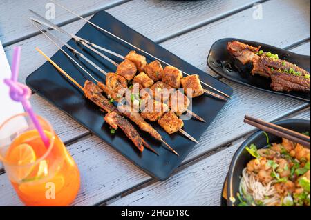 Tofu cinese e barbecue con ali di pollo serviti su un piatto in una vista dall'alto del ristorante. Barbecue asiatico Street food astratto, popolare spuntino notturno Foto Stock