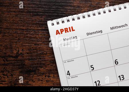 mese di aprile in calendario tedesco o pianificatore su scrivania in legno Foto Stock