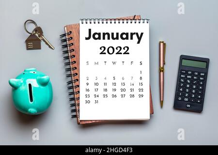 Calendario aperto Gennaio 2022, Piggy banca, calcolatrice, penna su sfondo grigio Vista dall'alto Flat Lay Educazione, obiettivi, risoluzioni, piano, piccola impresa proprietaria Foto Stock