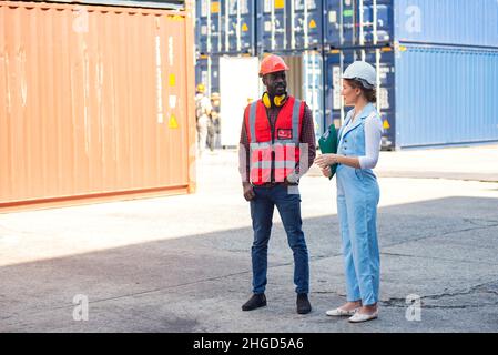 Donna d'affari e ingegnere parlare e controllare il carico contenitori scatola da carico nave da trasporto Cargo per l'esportazione di importazione. Spedizione in banchine. Foto Stock