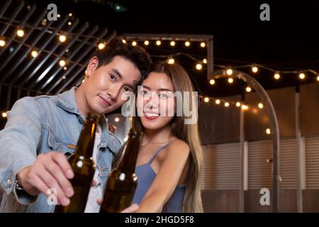 felice asiatico adolescente coppia uomo e donna in amore bere birra alcol e tostatura bottiglia in festa. giovane coppia felice amore e romantico Foto Stock