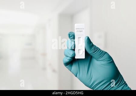 Mano con guanto che tiene un dispositivo di test rapido per COVID-19 con risultato negativo del test. Foto Stock