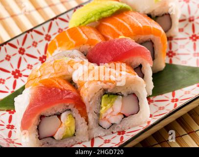 Da sopra di piastra in ceramica con gustosi rotoli di arcobaleno Uramaki posti sul tavolo Foto Stock