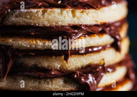 Pancake americani con ripieno di cioccolato con menta e nocciole su un piatto blu con fondo scuro Foto Stock