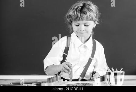 Ritratto ragazzo scuola capretto che fa i compiti d'arte, tenendo matita, scrittura. Bambino ragazzo che attingeva alla scuola elementare. Bambini arte, creatività bambini. Foto Stock