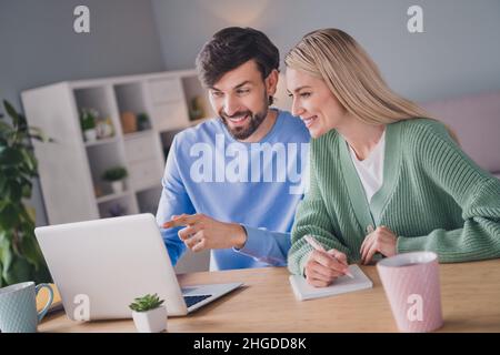 Ritratto di due attraente gente allegra usando il laptop che sceglie ordinare il servizio di fotoricettore delle merci a casa all'interno Foto Stock