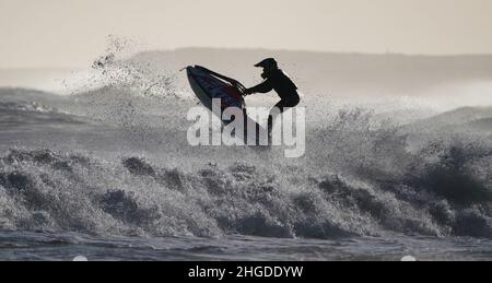 Un jet skier salta le onde al largo della costa di Blyth nel Northumberland. Data foto: Giovedì 20 gennaio 2022. Foto Stock