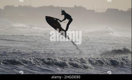 Un jet skier salta le onde al largo della costa di Blyth nel Northumberland. Data foto: Giovedì 20 gennaio 2022. Foto Stock