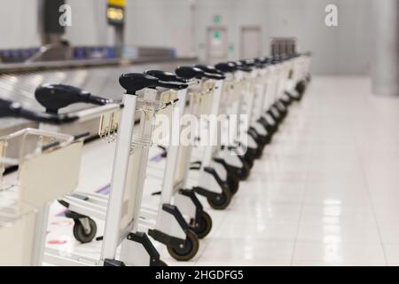 Parcheggio gratuito per i bagagli all'aeroporto dietro la linea di avvertimento nell'area di ritiro bagagli del terminal. Foto Stock