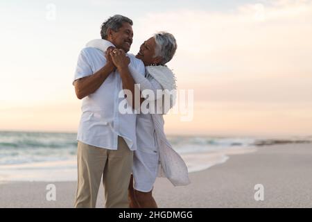 Allegro giovane coppia multirazziale senior che si guarda l'un l'altro mentre abbraccia durante il tramonto Foto Stock