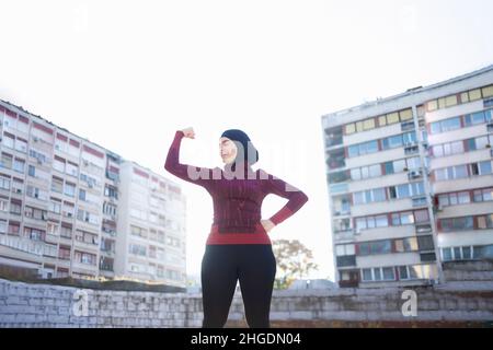 Giovane e felice donna musulmana che esprime la sua forza interiore Foto Stock