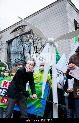 Un attivista ambientale indossa una fessura di cartone con la faccia di Markus Soeder e finge di tagliare una prop di turbina eolica. Il 20 gennaio 2022 il leader del partito Verde Buendnis 90/Die GRUENEN, Vice Cancelliere e Ministro dell'economia e della protezione del clima Robert Habeck ha visitato il Presidente del Ministro bavarese nella Cancelleria di Stato bavarese a Monaco di Baviera, in Germania. Di fronte ad essa, gli attivisti ambientali hanno protestato per l’energia eolica e contro la regola del 10H. La regola del 10H dice che la distanza tra una turbina eolica e le case deve essere 10 volte l'altezza. Il mese di gennaio Foto Stock