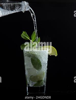 Un bicchiere di acqua frizzante con menta e una fetta di lime Foto Stock