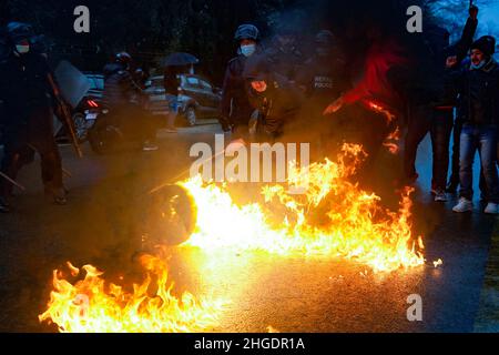 Kathmandu, Nepal. 20th Jan 2022. Un poliziotto riota tenta di destare un fuoco acceso dai quadri del Partito Comunista del Nepal durante una protesta contro l'aumento dei prezzi del carburante a Kathmandu, Nepal, giovedì 20 gennaio 2022. (Credit Image: © Skanda Gautam/ZUMA Press Wire) Foto Stock