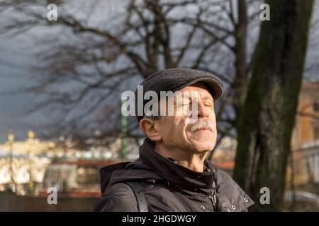 L'uomo adulto si alza nel parco a fine autunno ed espone i raggi del sole Foto Stock