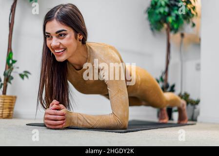 Fit, attiva e attraente giovane donna ragazza che si allunga prima o dopo l'esercizio a casa mantenendo sano e in forma modo di vita e il fisico quotidiano Foto Stock